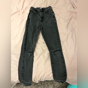 High waisted black skinny jeans with two holes at the knees.